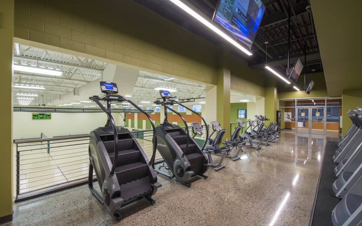 A gym with treadmills, elliptical machines and televisions.