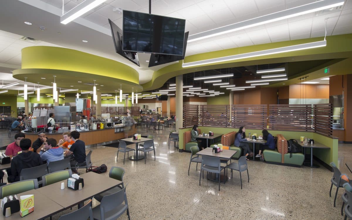 The interior of a cafeteria with people sitting at tables.