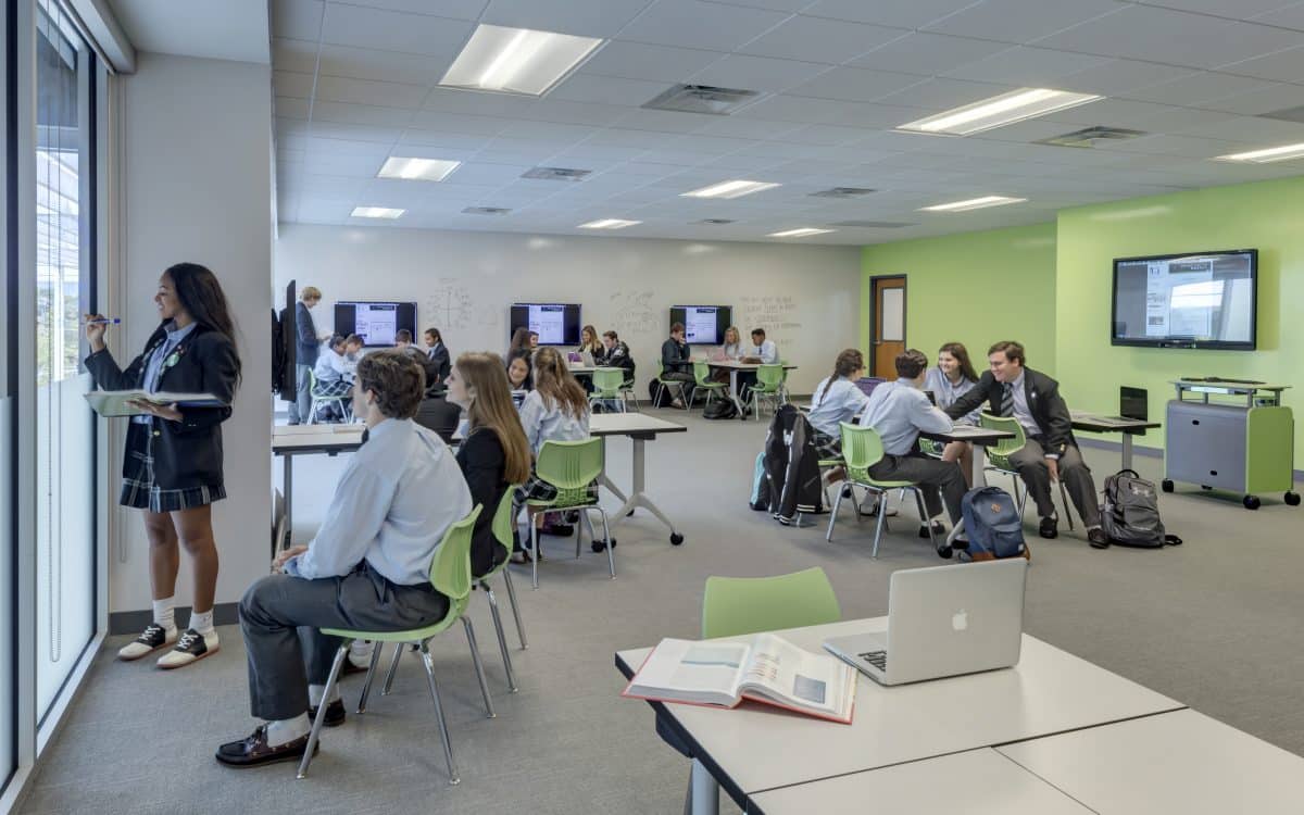 A classroom with people sitting at desks and laptops.