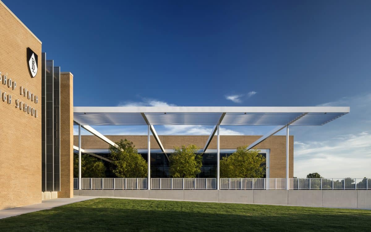 A rendering of a school building with grass and trees.