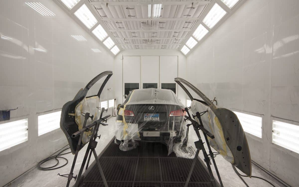 A car is being painted in a paint booth.