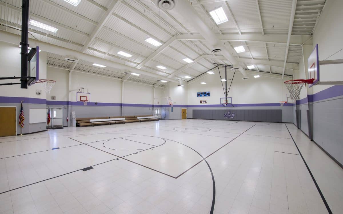 A gym with a basketball court and benches.