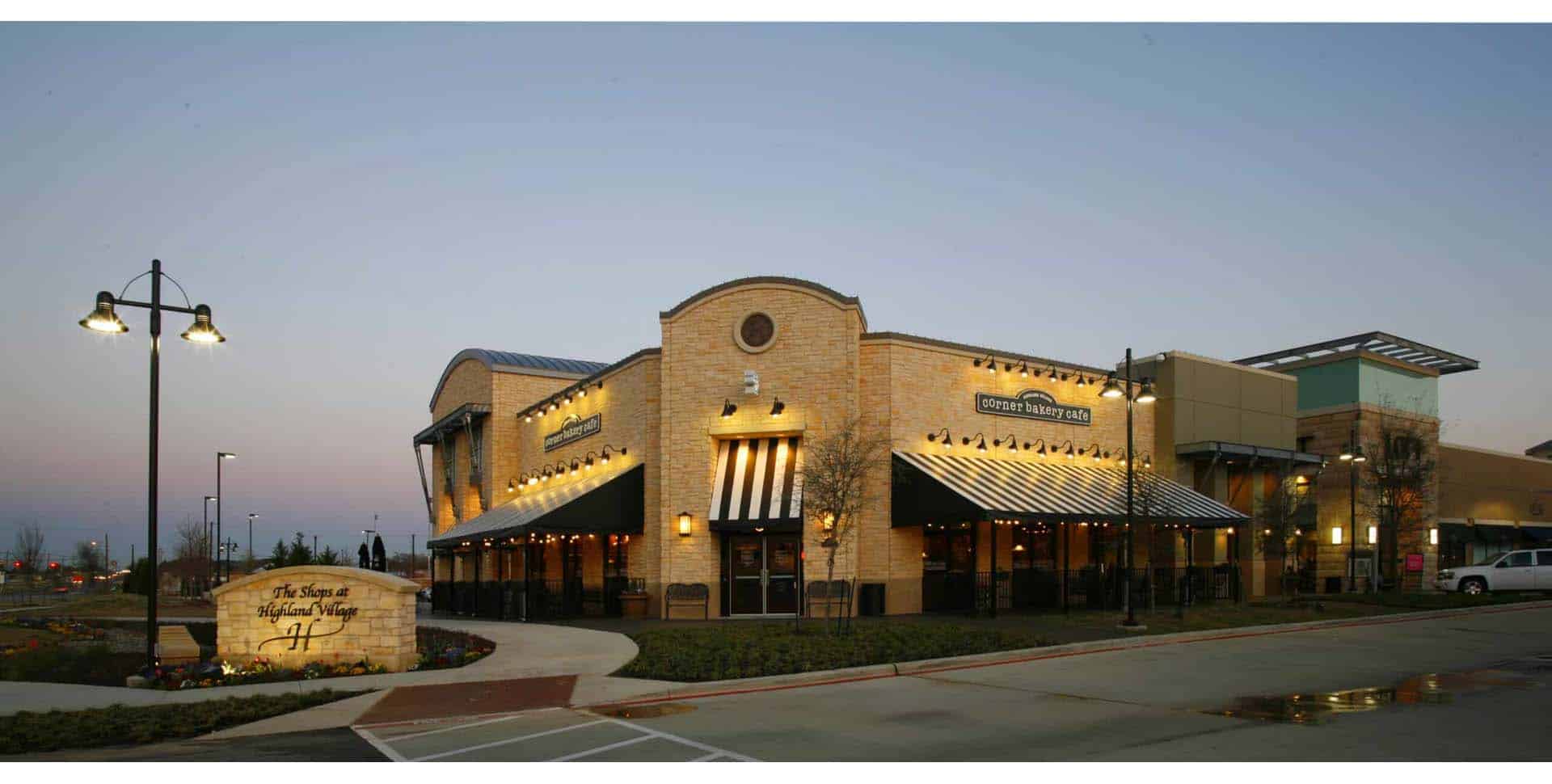 A brick and stucco restaurant building with striped awnings, exterior lighting, and a sign reading “Stone Werks Big Rock Grille” at the entrance.