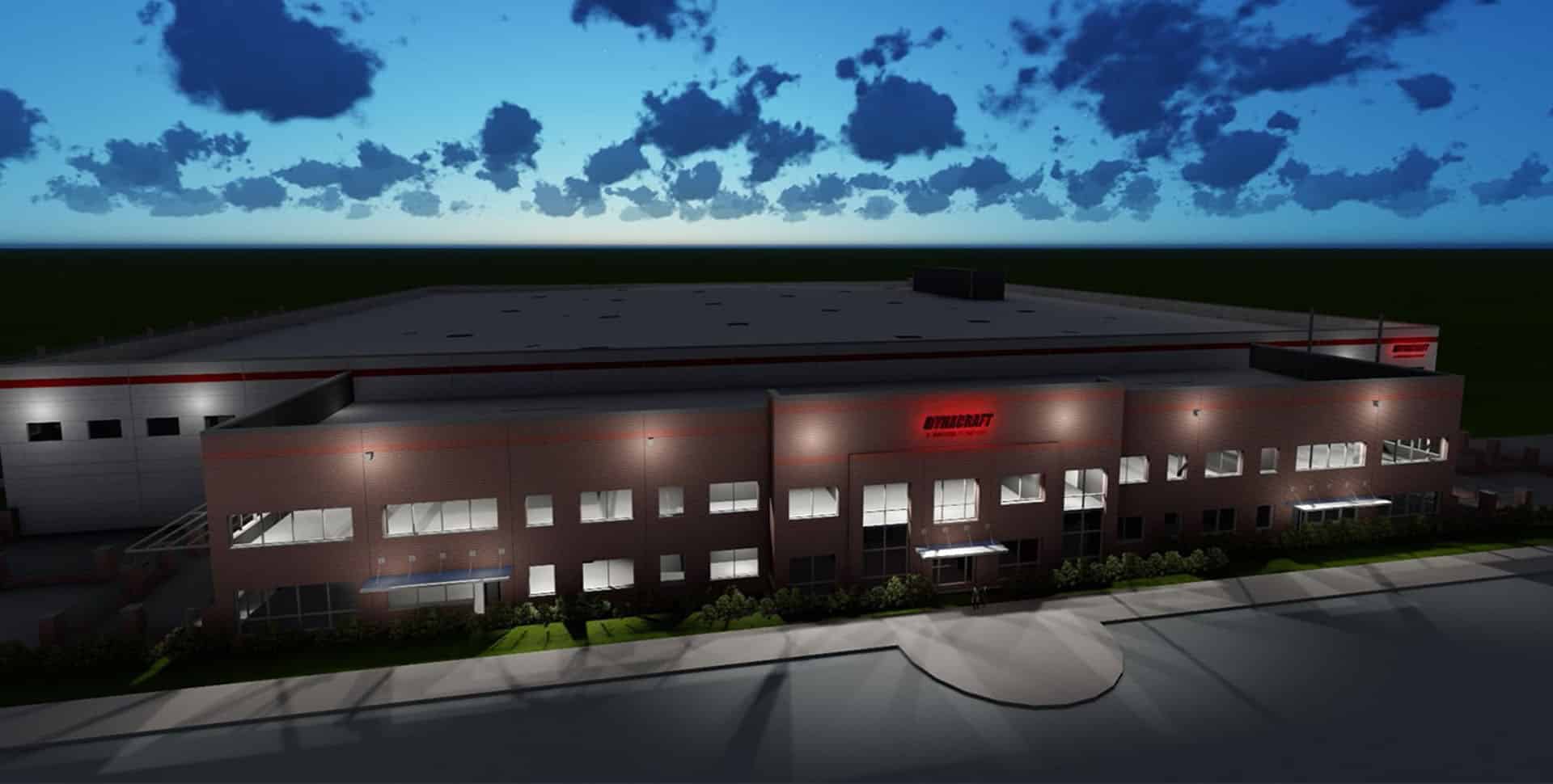 A large, modern industrial building with illuminated windows and the sign "KIMRAY" on the facade, viewed at dusk under a partly cloudy sky.