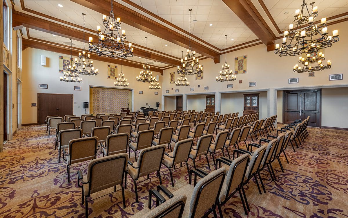 A large conference room with rows of chairs and a chandelier.