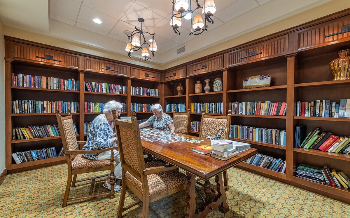 Two people sitting at a table in a library.