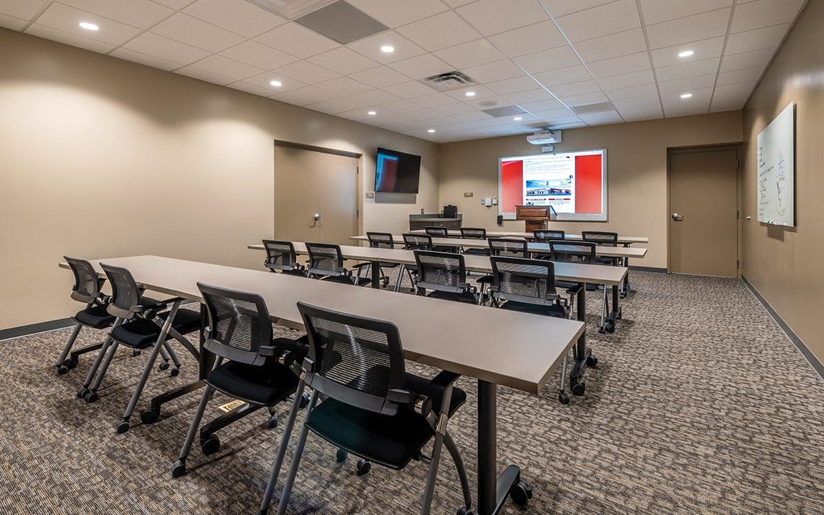A conference room with a large screen and chairs.