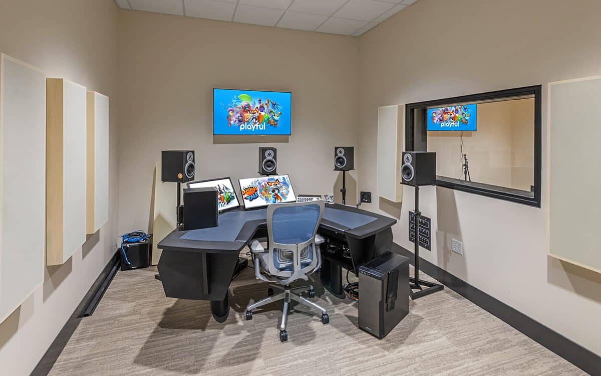 A recording studio with a desk and monitors.