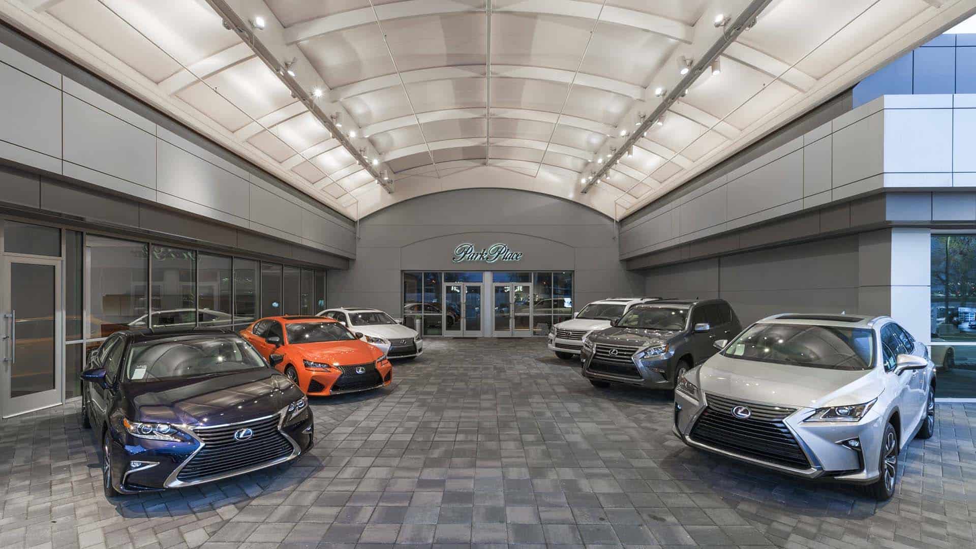Indoor car showroom featuring several Lexus vehicles parked on a tiled floor, with glass doors and the "Pine Box" sign visible at the back.