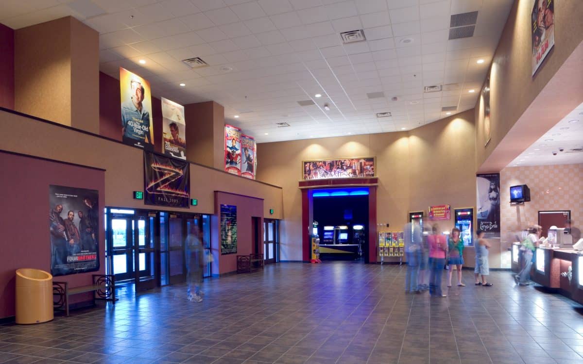 The lobby of a movie theater with people walking around.