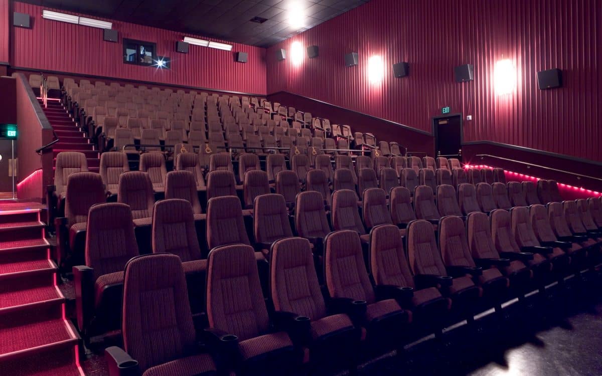 A movie theater with rows of seats and red lights.