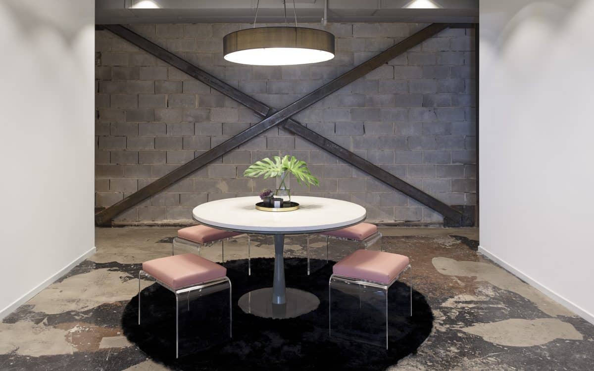 A round table in a room with two pink stools.