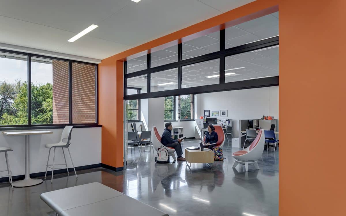 An orange and white office with people sitting in chairs.