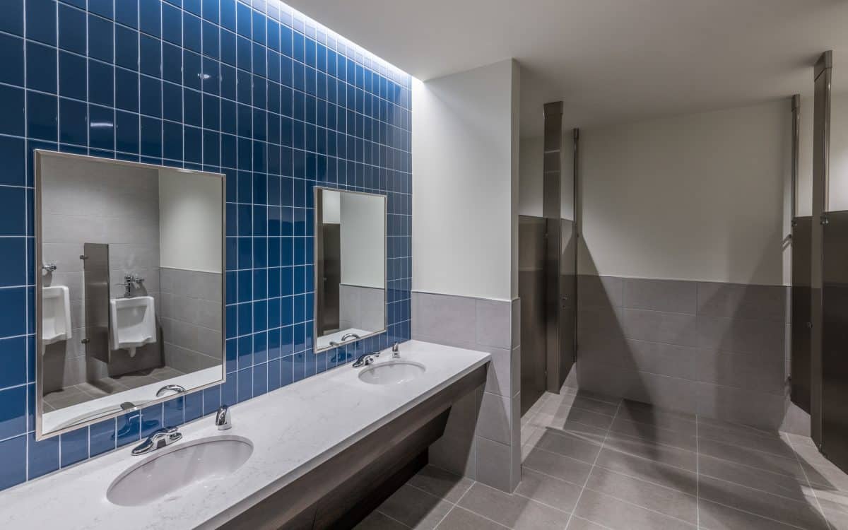 A blue tiled bathroom with two sinks and mirrors.