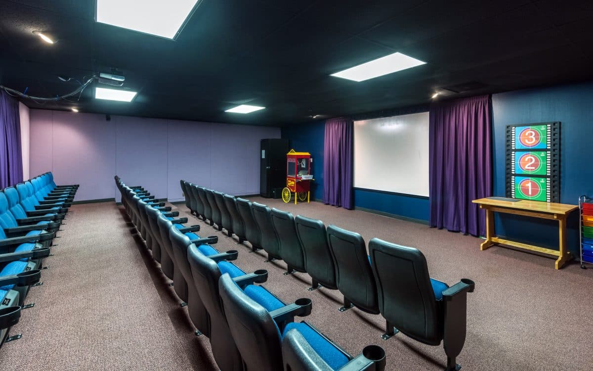 A theater with rows of chairs and a projection screen.