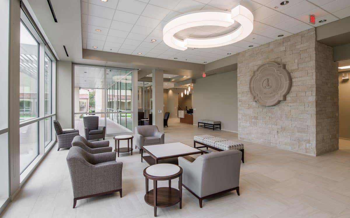 A lobby with chairs and tables and a circular light fixture.