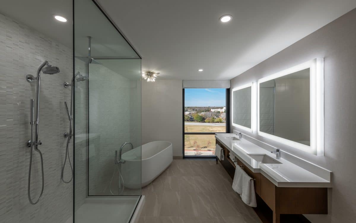 A bathroom with glass shower doors and a view of the city.