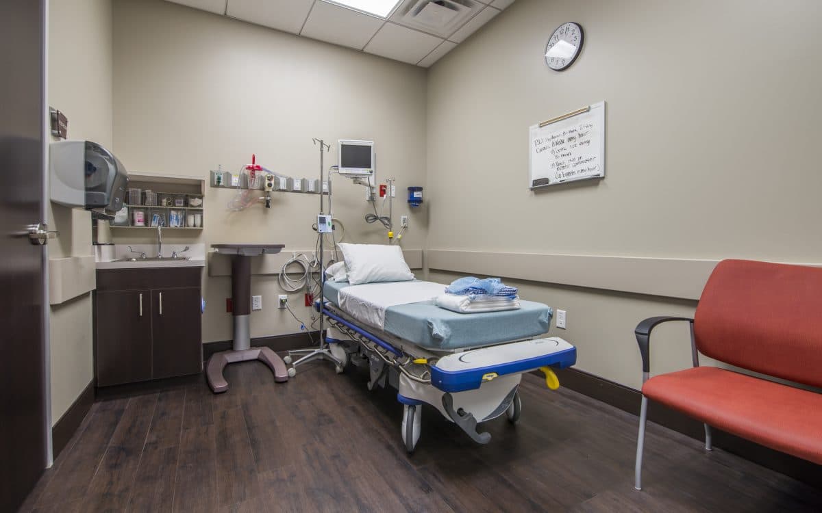 A hospital room with a bed and a chair.