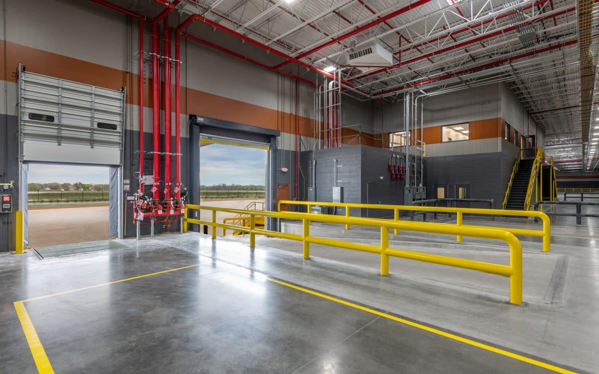 The inside of a large warehouse with yellow railings.