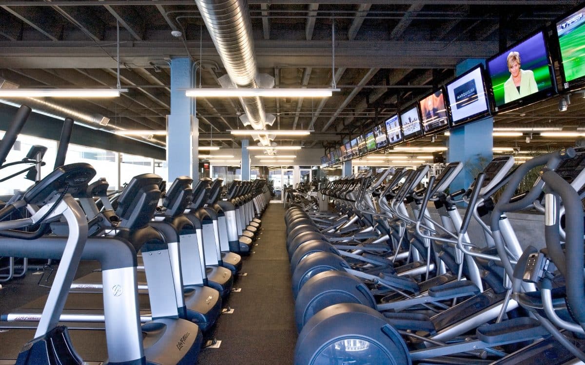 A gym with many tread machines and televisions.