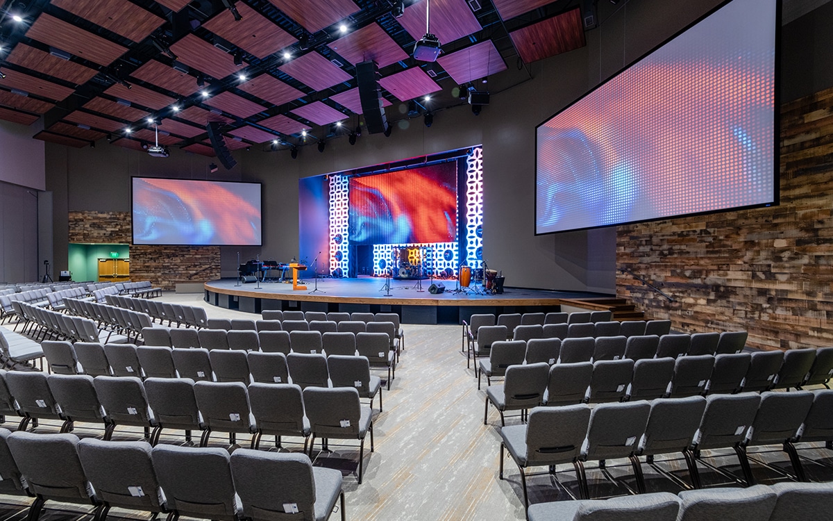 A church auditorium with a large screen and rows of chairs.