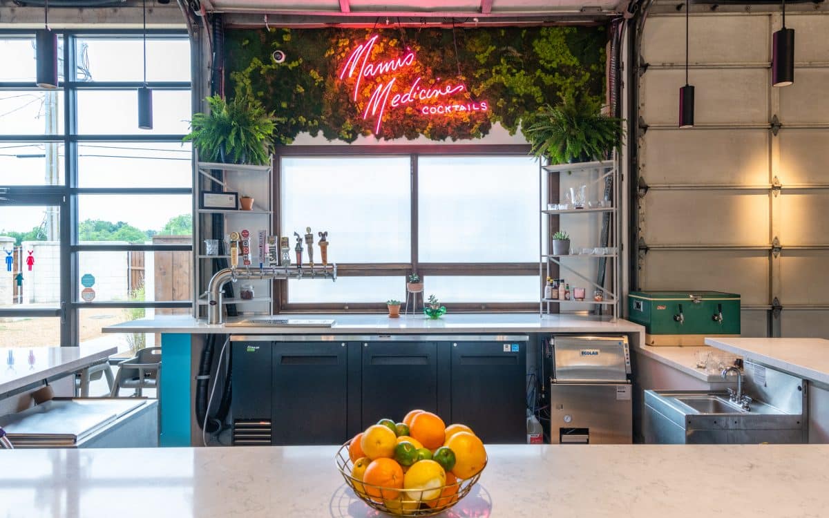 A kitchen with a bowl of oranges and a neon sign.