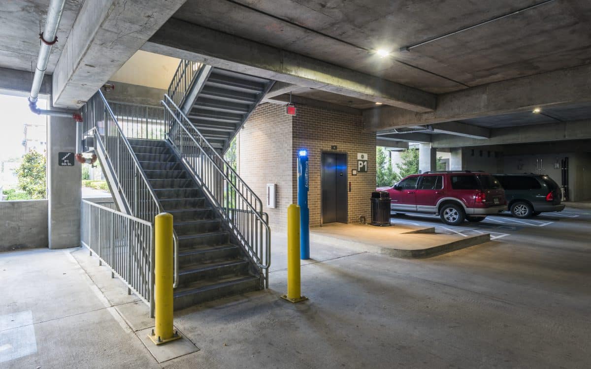 A parking garage with stairs and a car.