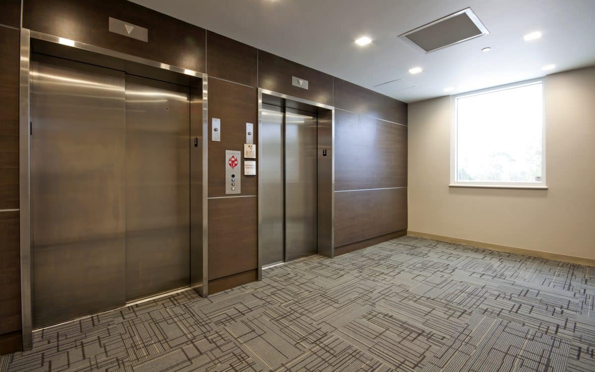 Elevators in an office building with a carpeted floor.