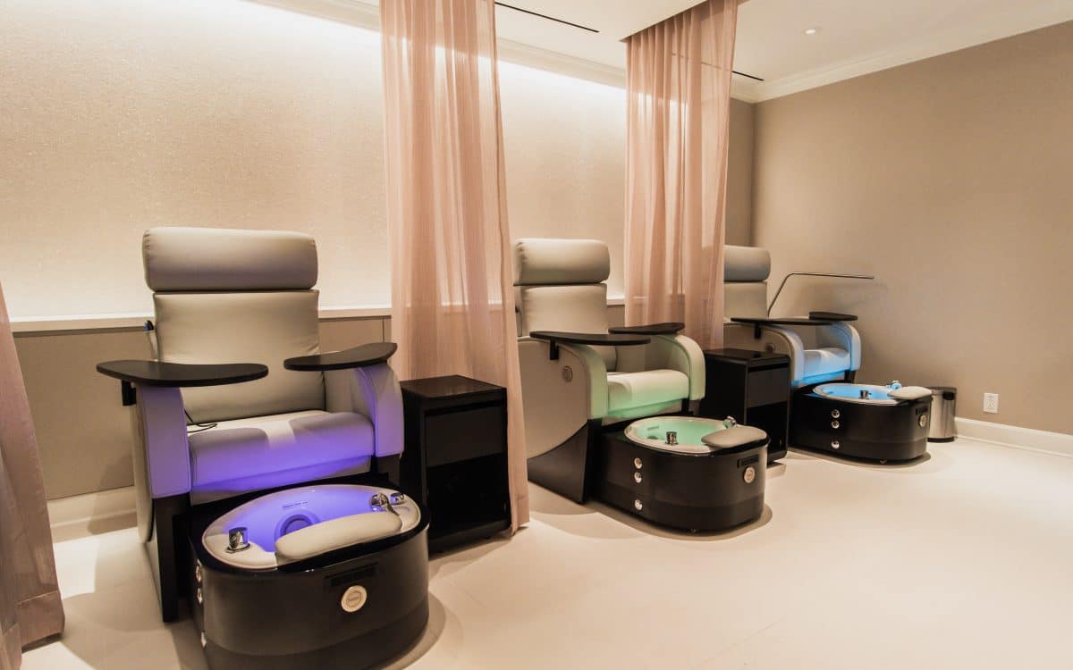Three pedicure chairs in a room with lights.