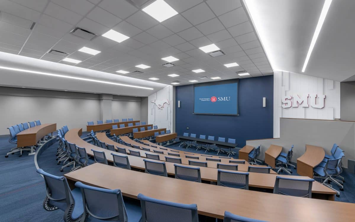 A conference room with blue chairs and a large screen.