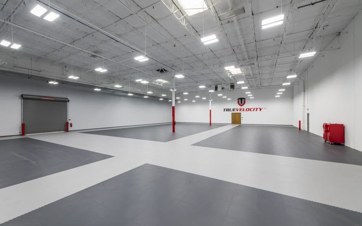 A large warehouse with a white floor and red lights.