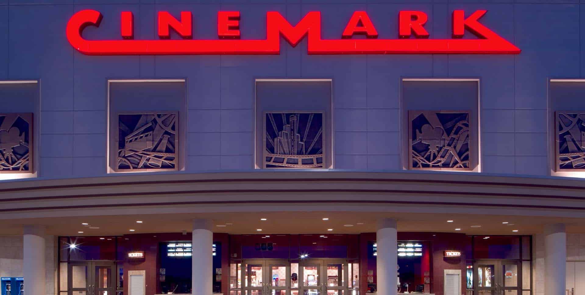 Cinemark movie theater exterior with large red illuminated sign above entrance and ticket windows below.