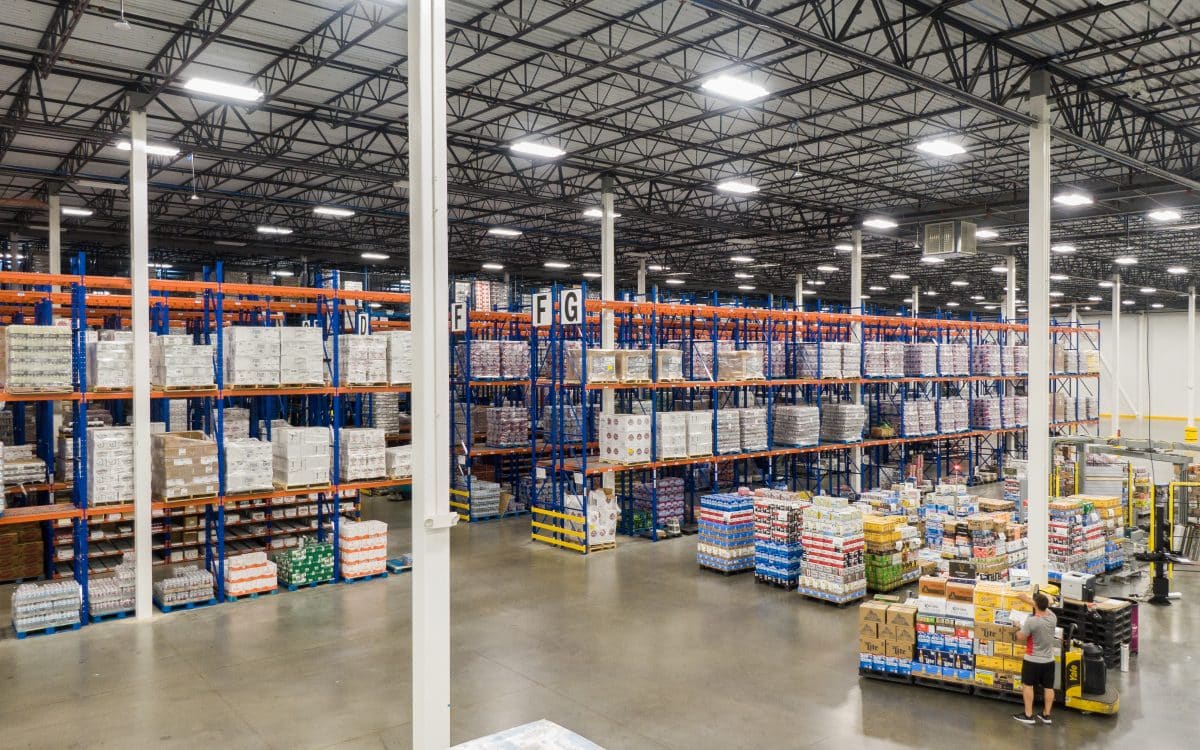 The inside of a large warehouse with shelves and pallets.