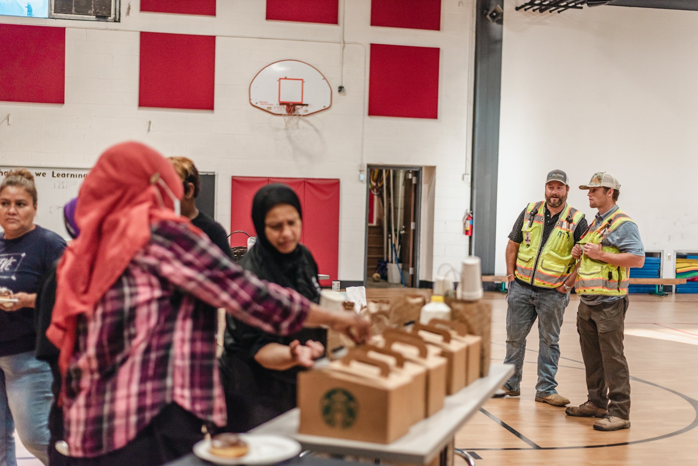 a group of teachers getting coffee at a table with two construction workers talking to the side